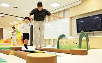 プレイルームで一緒に遊ぶ子どもと保護者