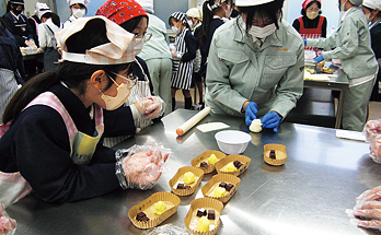 作業台の上で一緒にパン作りを行う児童と生徒たちの様子